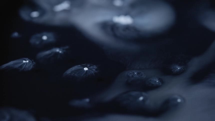 White smoke floating and swirling around dry ice over a black reflecting surface
