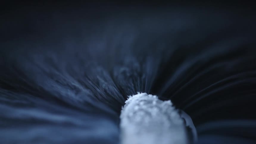 Vapor tendrils flow from white powder in blackness