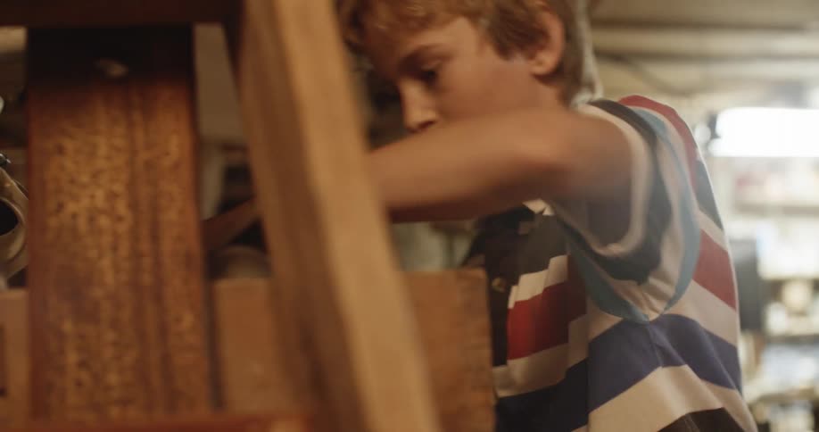 A boy playing in the basement takes a hose from a box