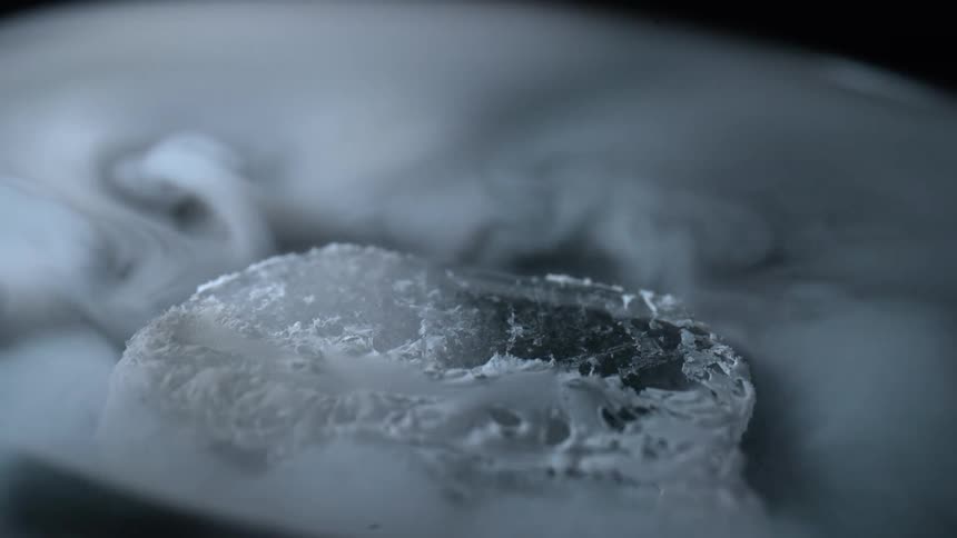 A single piece of dry ice is evaporating quickly as it sits atop a thin layer of water