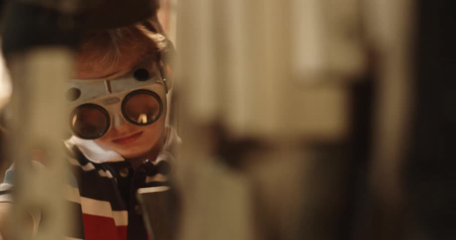 Kid wearing goggles shoots sparks into air while working
