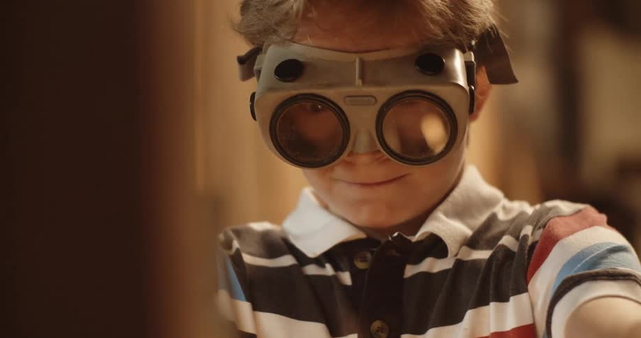 Young boy wearing goggles playing with sparklers inside a room at home