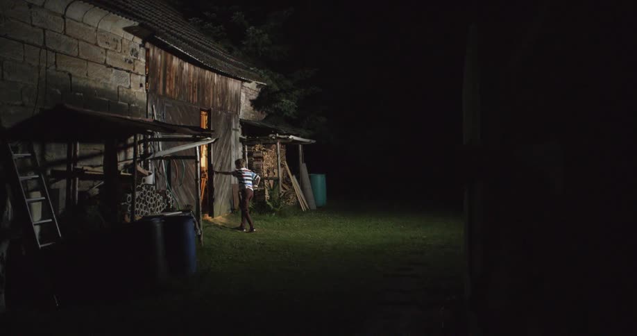 A boy enters the barn at night