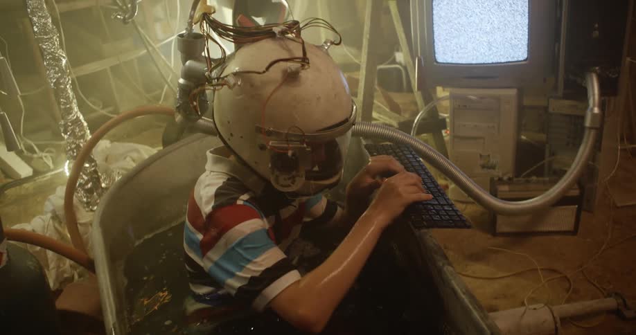 A boy is playing in the tub while wearing a helmet