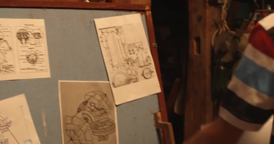 Young boy places blueprints over a blackboard in the basement