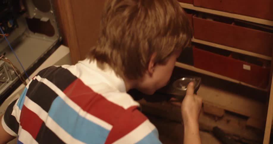 A teenager blows dirt and dust off a container with four circular sections