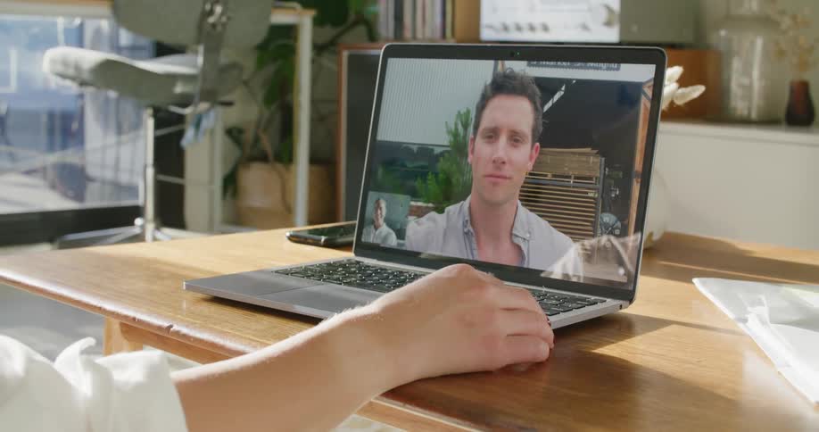 A woman at her desk during a video call on her laptop with a man