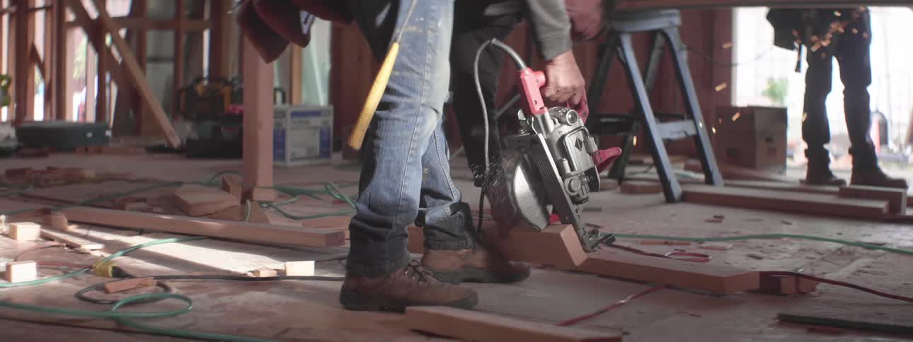 Worker cutting a piece of wood using a power tool on a construction site
