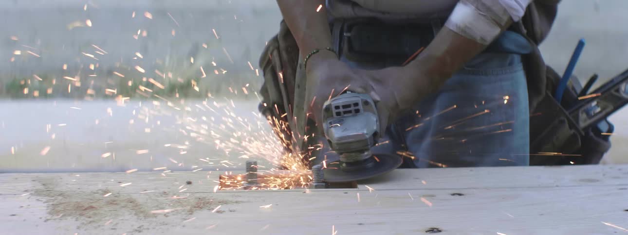 A person using an electric saw to cut a bolt with sparks