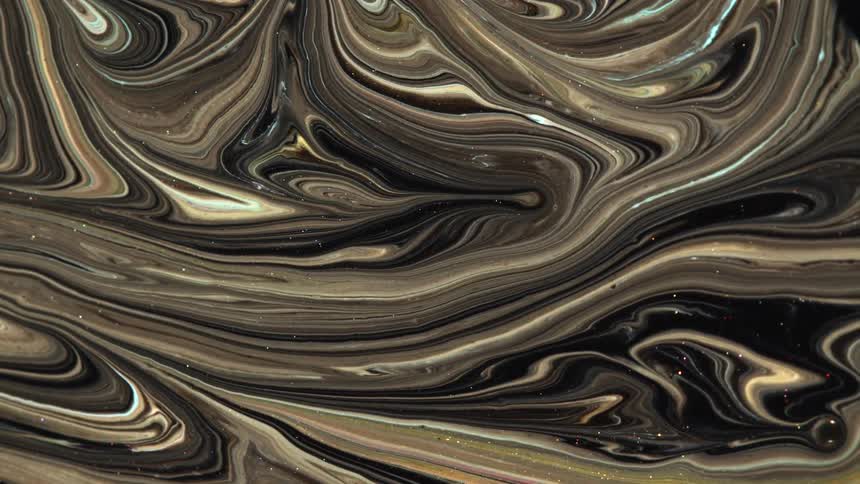 Swirls of brown and black sparkling liquid ink forms psychedelic abstract paterns