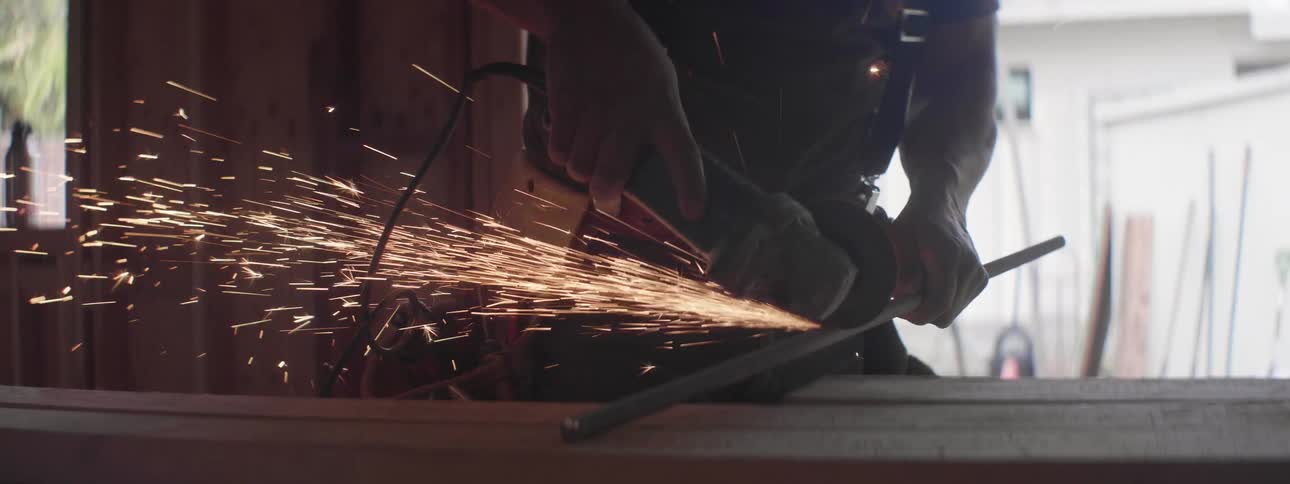 Construction worker cutting a metal rod using a power tool inside a house
