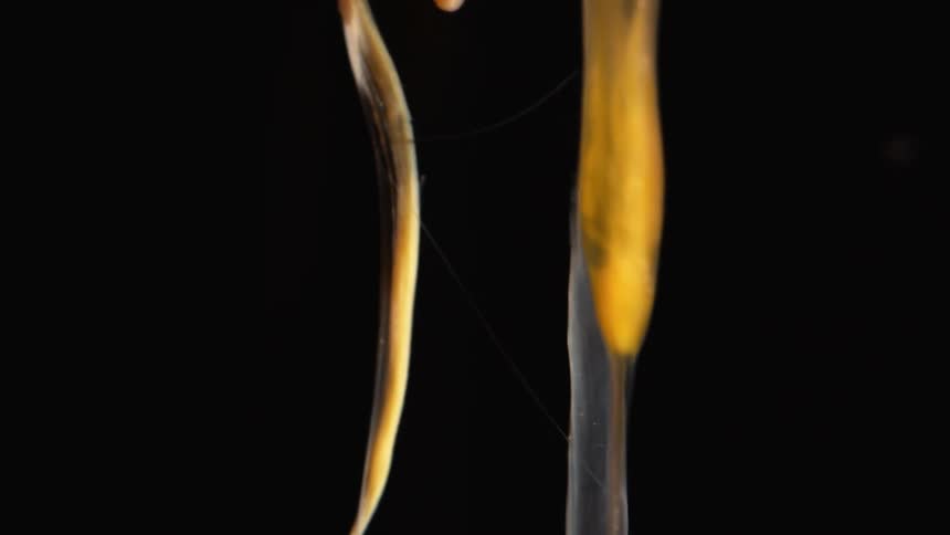 Gold and silver abstract tubes glow and fade in light and shadow as they turn