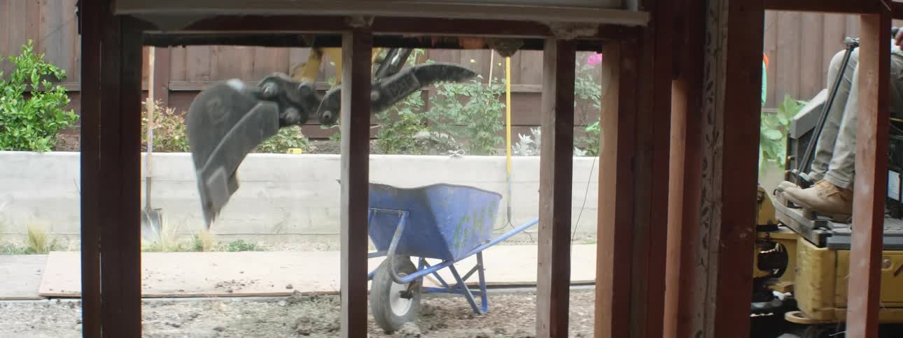 An excavator in a construction site moves dirt from the ground into wheelbarrows