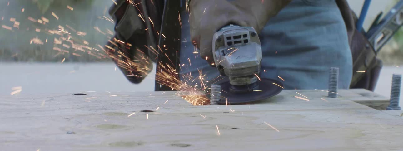 A construction worker is cutting a sheet of wood