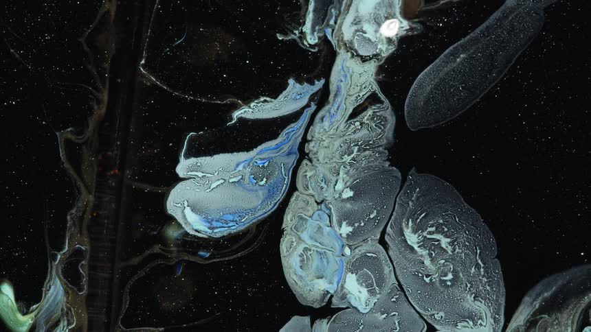 Metallic paint colors blend and swirl together to form abstract patterns