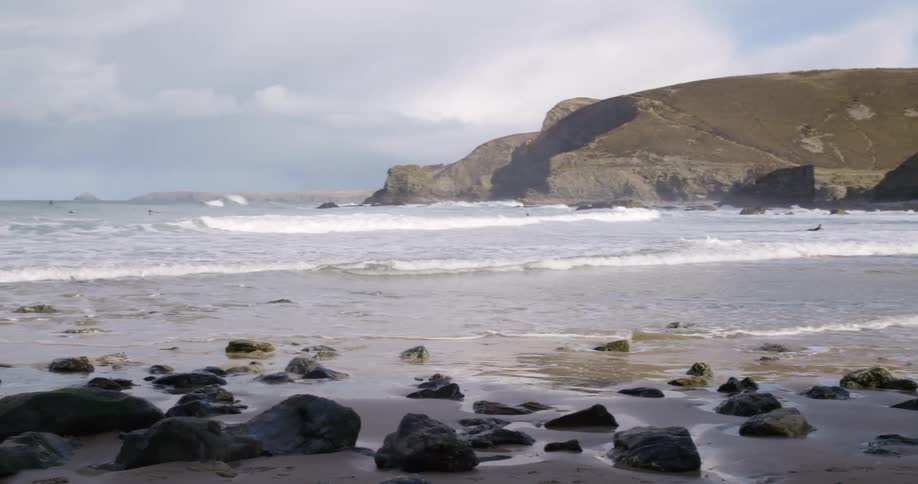 Ocean waves roll into a rocky beach on a cloudy day