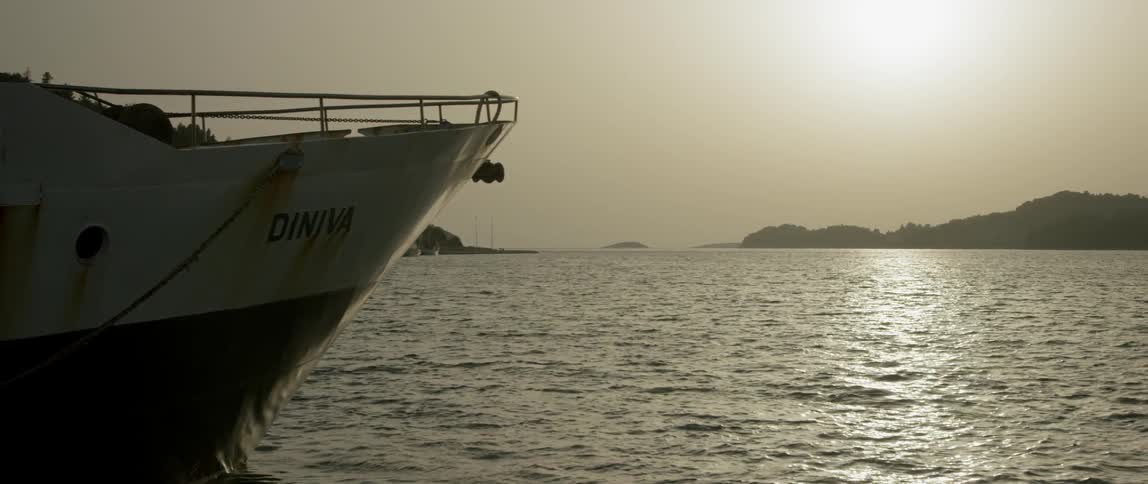The edge of a boat can be seen in the water at sunset