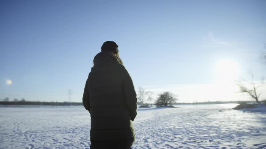 Person wearing fur coat walks over snow covered ground during the day