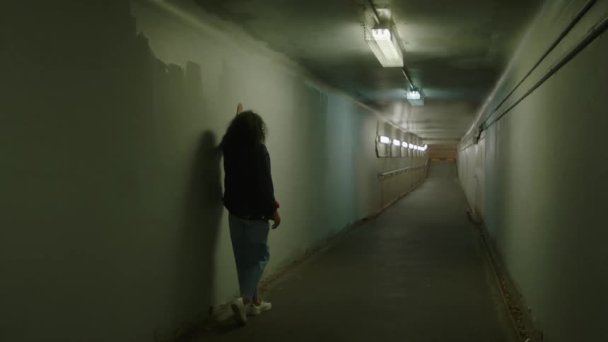 A woman walks down the dark hall