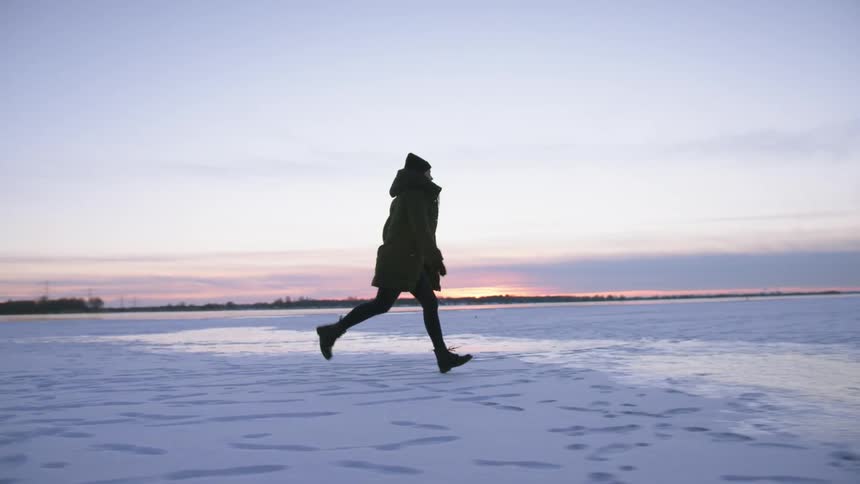 A woman runs across a snow covered field