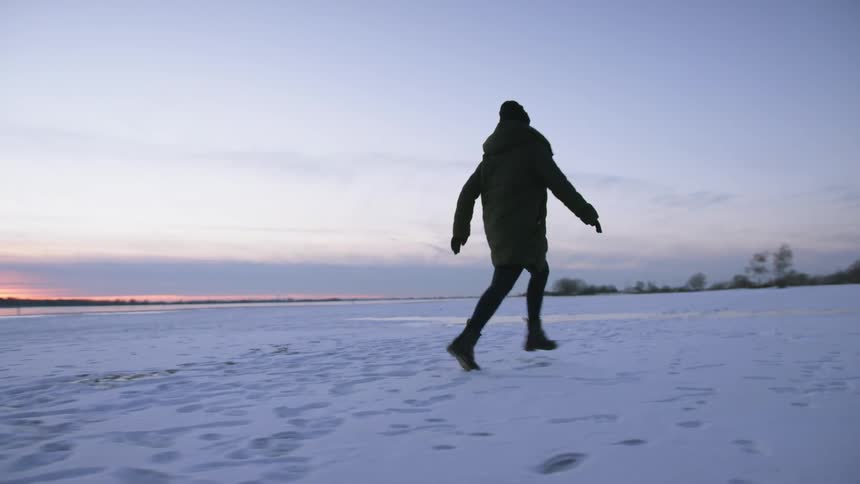 A woman is jogging outdoors in winter at dusk