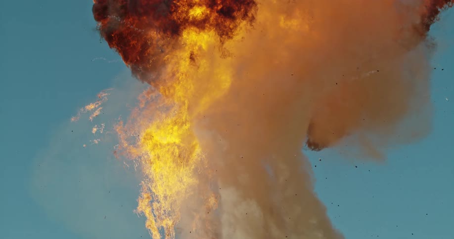 An explosion of flames and smoke rise high into the sky above the rubble on the ground