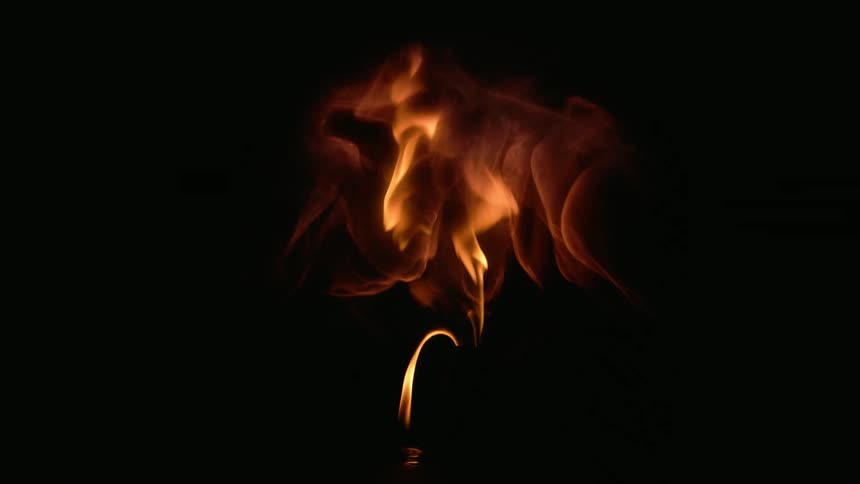 Fire explodes from a candle and the flames are contained inside a clear globe in the darkness