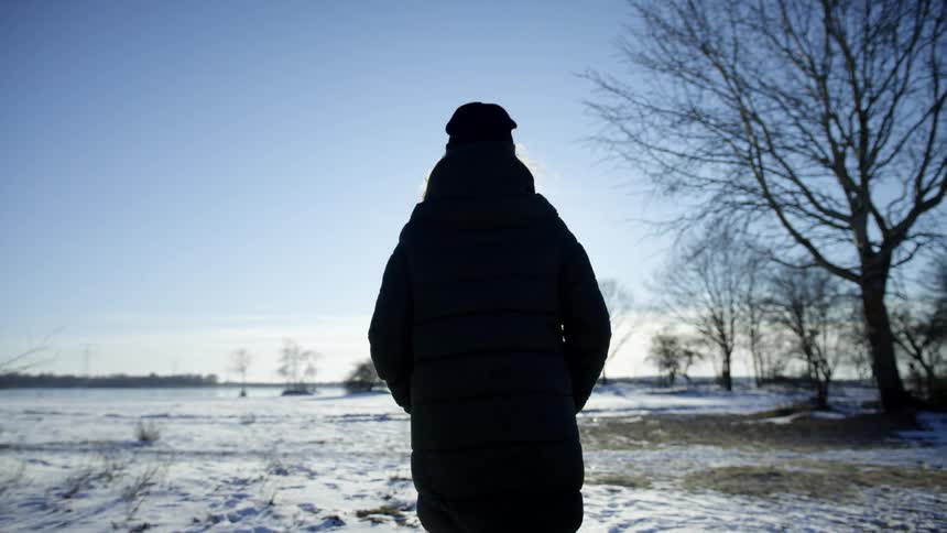 A woman is walking outdoors and wearing a jacket in winter