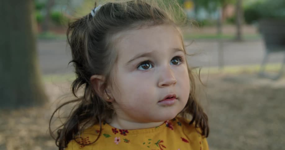 A toddler girl standing outside in summer