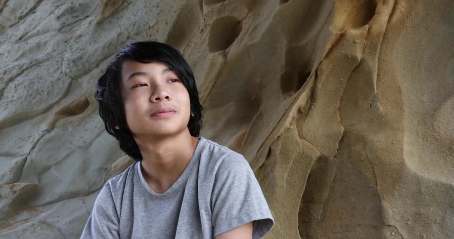 Young boy reclined on a sand dune looking at the horizon