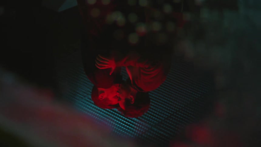 Reverse reflection of a young gay couple kissing under red lights