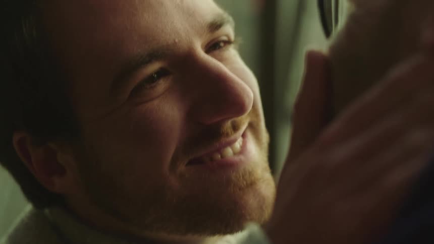 Male couple tenderly smiling and kissing inside a room