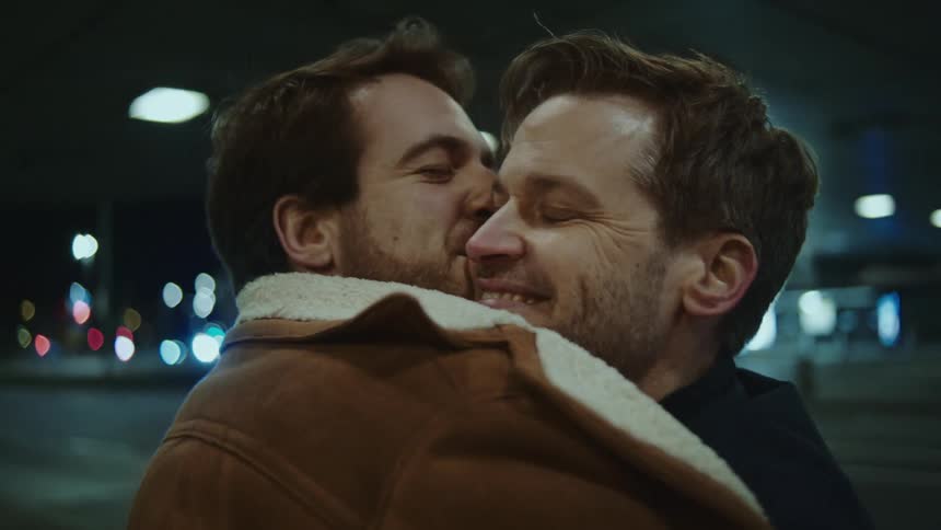 Two men are hugging and kissing at night