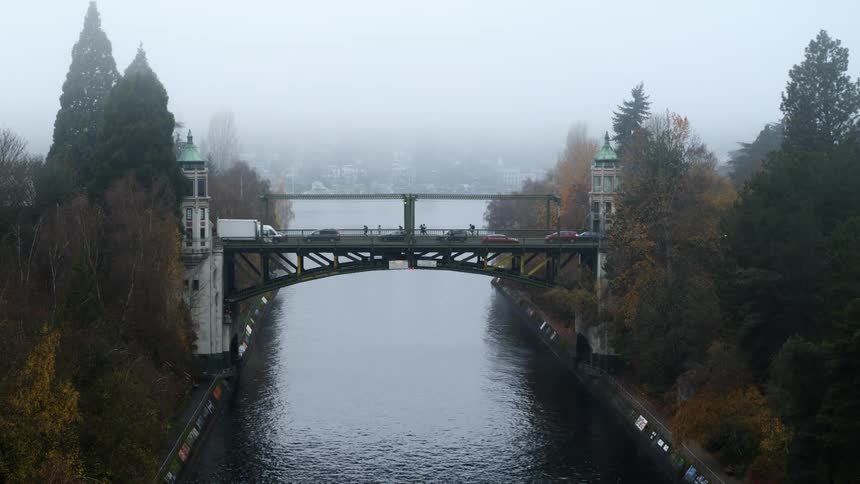 Slow push toward a beautiful drawbridge as vehicles and pedestrians cross during a foggy morning commute