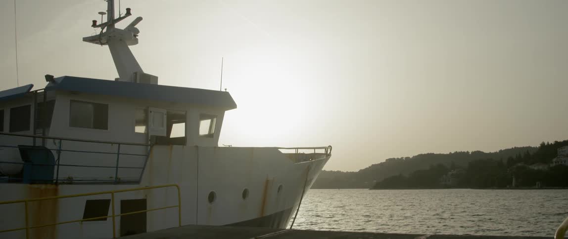 A boat floats on a lake with the bright sun shining in the background