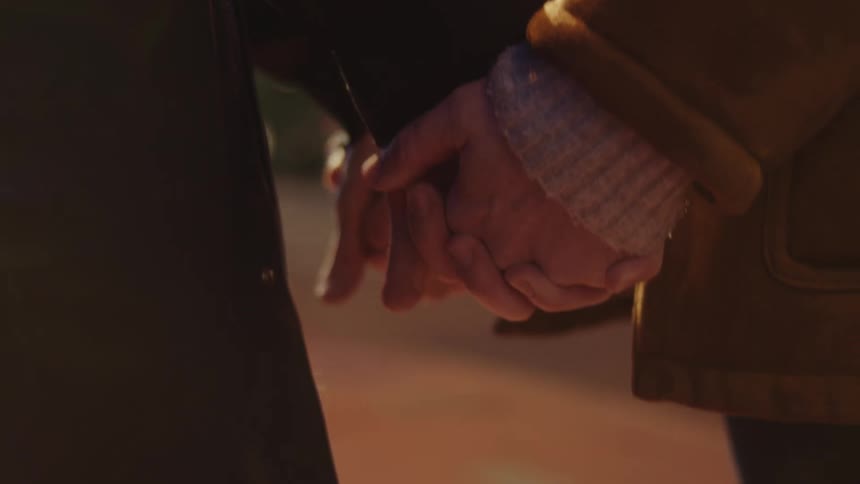 Couple holding hands on the street of a city at night