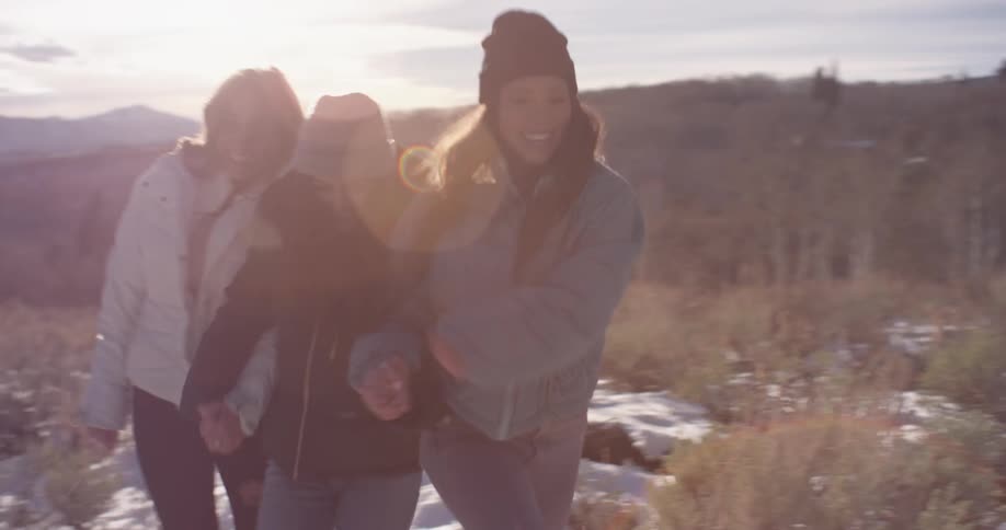 Three women run through the snow on the hill