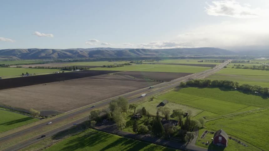 Cars and trucks on an interstate highway traveling through fertile and lush farmland