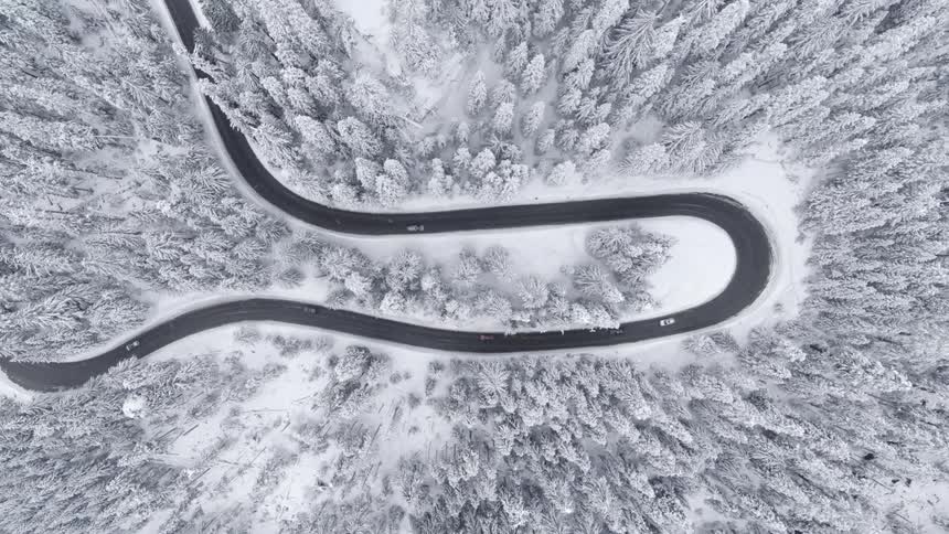 Birds eye view of traffic driving along a hairpin curve on a steep mountin road