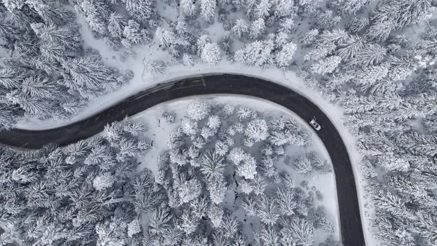 Ascending twist as a car drives along a winding road through snow covered trees