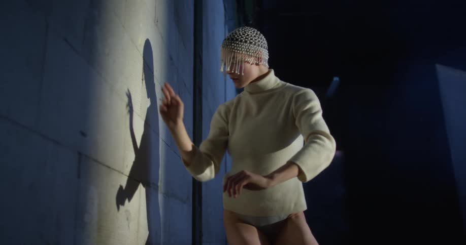 Woman dances facing her own shadow cast by spotlight