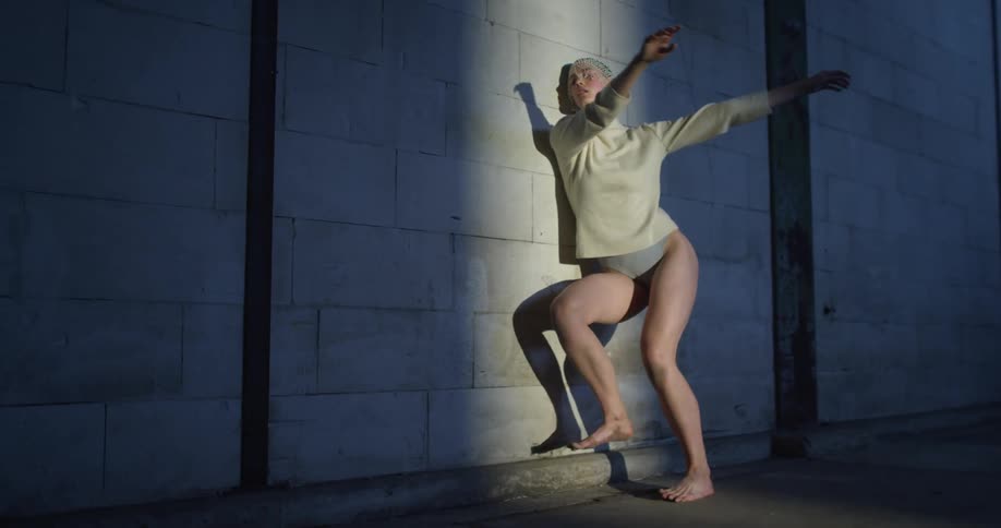 A woman is dancing against the wall