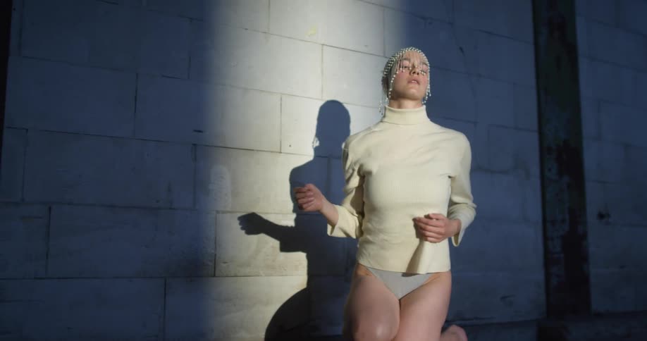 A woman in a room dancing by a wall