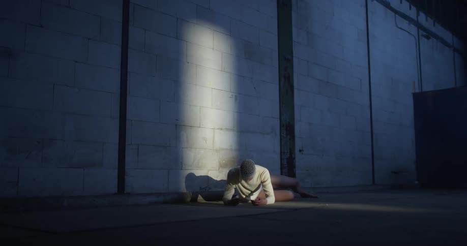 Dancer resting on the floor of a dimly lit abandoned warehouse