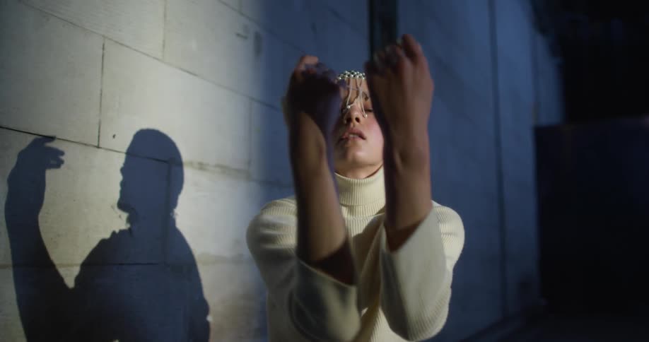 A female dancer kneeling in the floor dancing in front of a wall in an abandoned warehouse