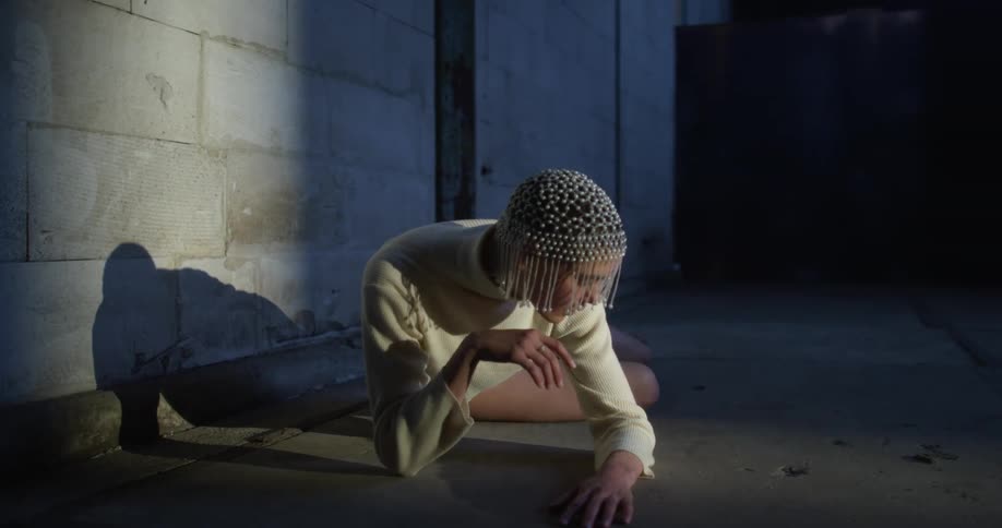 Dancer performing cat like movements on the floor of a dimly lit abandoned warehouse