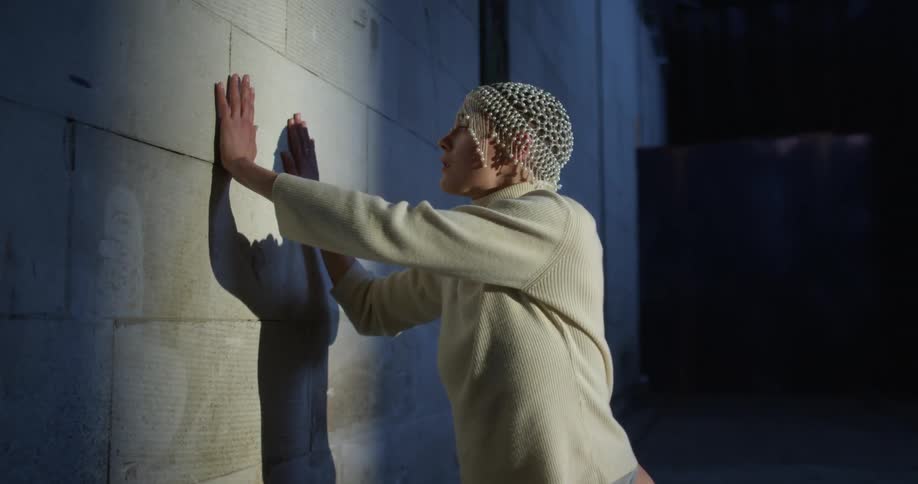 A woman is dancing next to a wall indoors