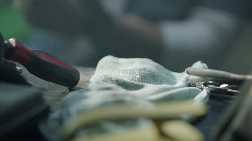 A person that is grabbing a tool off a table