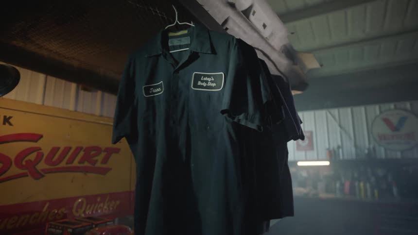 Several work shirts hang in an empty car body shop