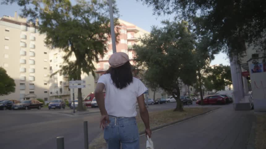 Young woman walking on the sidewalk on a residential area in the city at morning